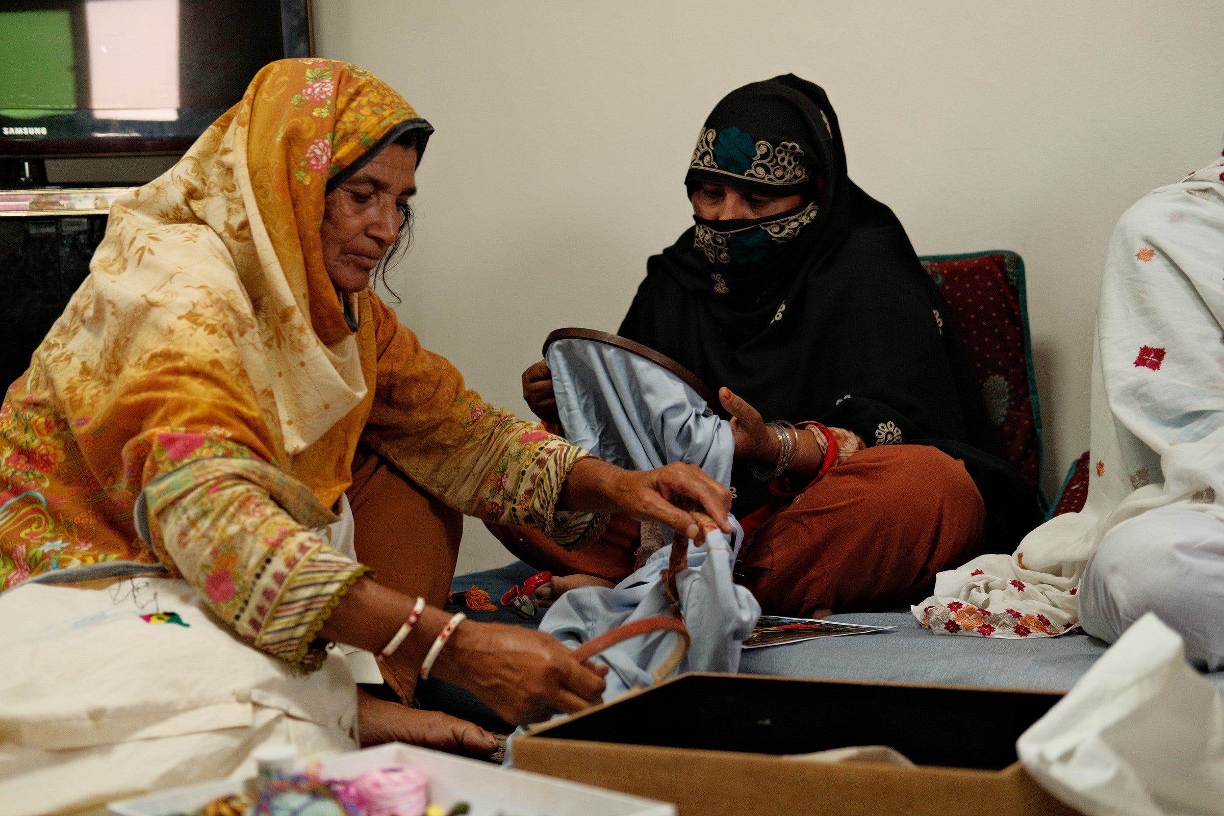A group of artisans examining hand-embroidered fabric