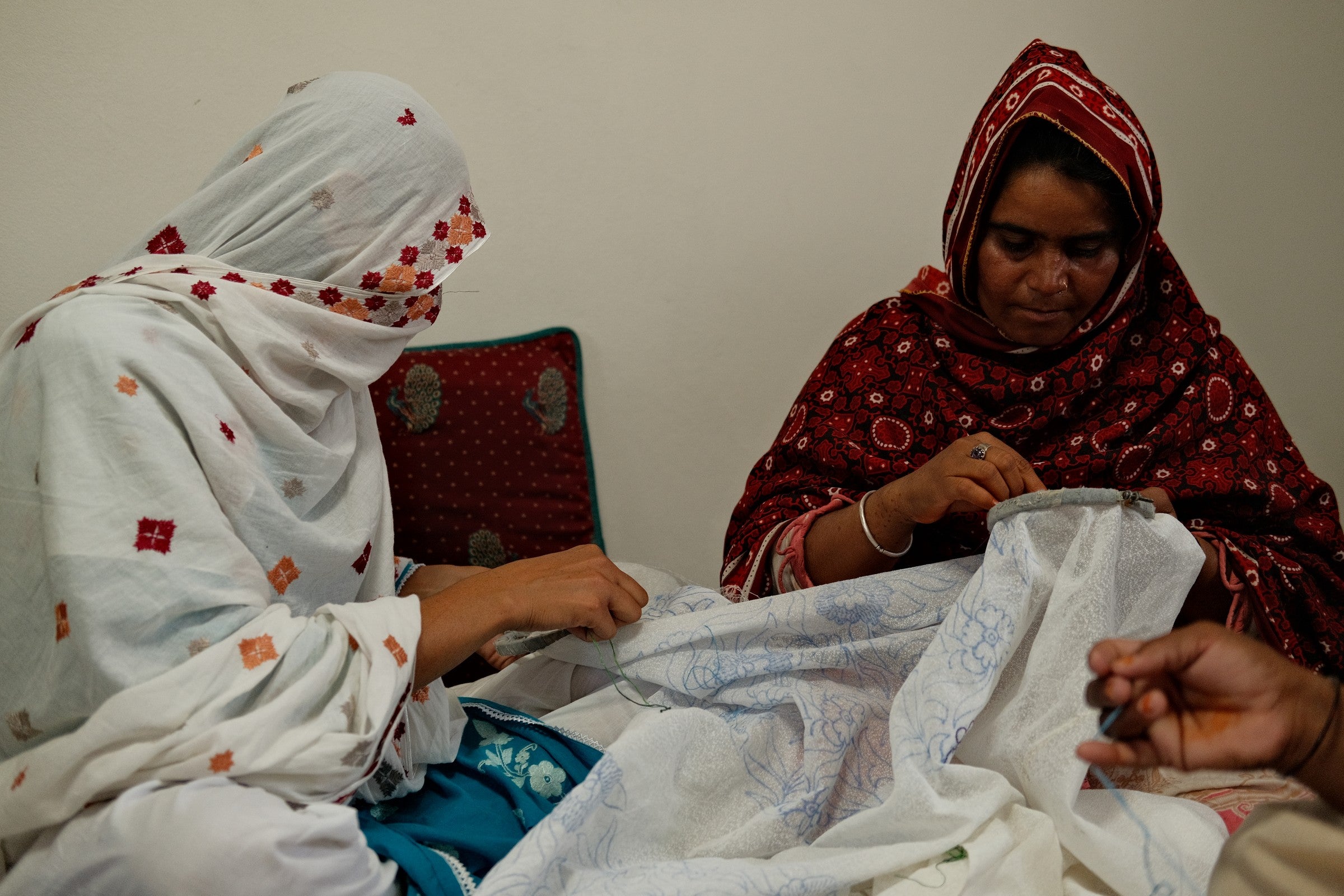 Two artisans working together on a hand-embroidered piece