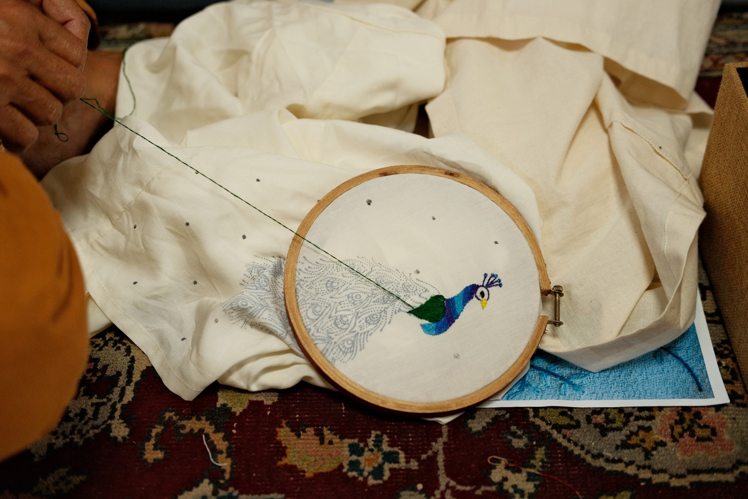 Close-up of peacock hand embroidery in a hoop